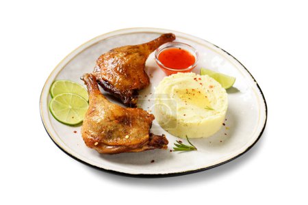 Téléchargez les photos : Jambes de canard fraîchement rôties confit servi avec purée de pommes de terre et tranches de lime. isolé sur fond blanc - en image libre de droit