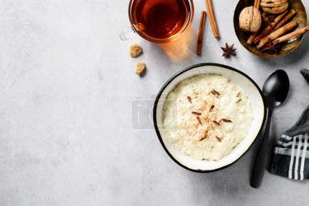 Photo for Fresh prepared rice pudding garnished with cinnamon flakes. Healthy breakfast for every day. Light gray background, top view - Royalty Free Image