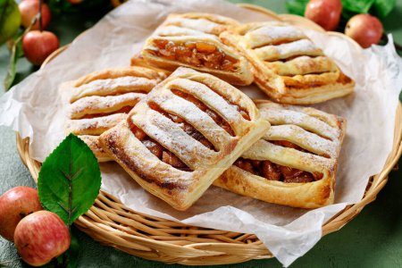 Photo for Homemade puff pastry pies filled with caramelized apples . green background - Royalty Free Image