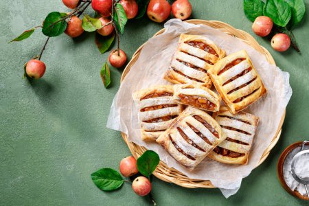 Photo for Homemade puff pastry pies filled with caramelized apples . green background. top view - Royalty Free Image