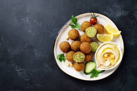 Photo for Plate of chickpeas falafel balls with hummus, vegetables  and lemon slices .Top view. - Royalty Free Image