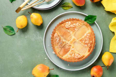Die klassische Birnen-Frangipane-Torte (Tarte Bourdaloue). Köstliches Herbst- und Wintergebäck voller Aromen und Konsistenz. Draufsicht, grüner Hintergrund