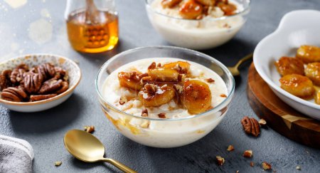 Photo for Fresh prepared rice pudding served with caramelized banana, honey and pecan nuts. - Royalty Free Image