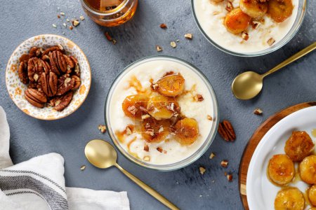 Photo for Fresh prepared rice pudding served with caramelized banana, honey and pecan nuts. top view - Royalty Free Image
