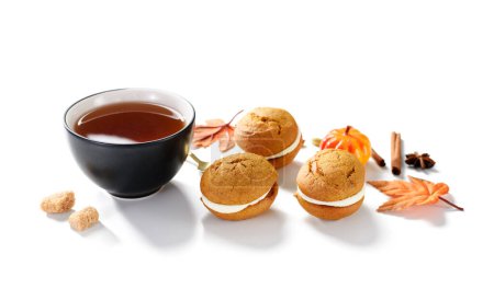 Photo for Pumpkin  sandwich cookies with cream cheese filling and cup of tea isolated on white background - Royalty Free Image