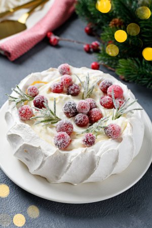 Foto de Tarta de merengue Pavlova decorada con arándano congelado y romero. Pastel para el evento de Navidad. - Imagen libre de derechos