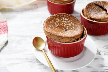 Photo for Freshly baked chocolate souffle with powdered sugar, french dessert. white wooden background - Royalty Free Image