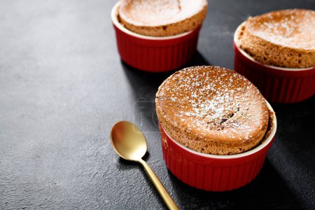 Téléchargez les photos : Soufflé au chocolat fraîchement cuit avec sucre en poudre. fond sombre - en image libre de droit