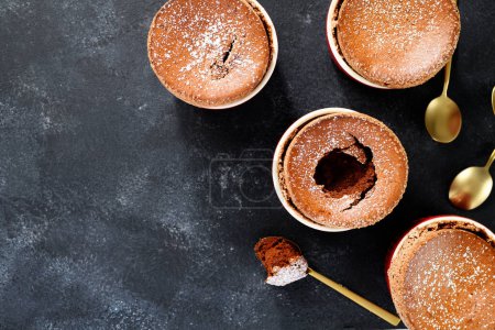 Téléchargez les photos : Soufflé au chocolat fraîchement cuit avec sucre en poudre. fond sombre, vue de dessus - en image libre de droit