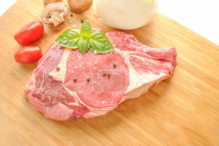 Téléchargez les photos : Steak cru Porterhouse aux légumes frais et basilic - en image libre de droit