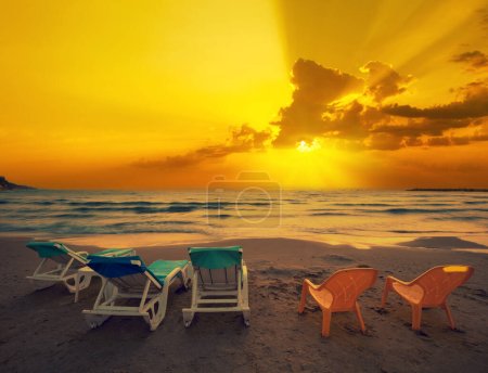 Seascape in the evening. Beach with chaise lounges at golden sunset