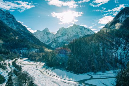 Mountain valley with the river in winter. The tops of the mountains are covered with snow. View of the Alps in Kranjska Gora at sunrise. Triglav national park. Slovenia, Europe