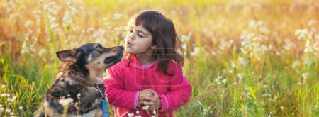 Glückliches kleines Mädchen mit Hund, das im Frühling auf der Blumenwiese spazieren geht. Horizontales Banner