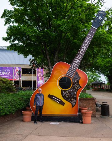 Foto de Nashville, Tennessee, Estados Unidos - 7 de mayo de 2022: Turista posando junto a la guitarra gigante en la entrada del popular lugar de música country Grand Ole Opry - Imagen libre de derechos