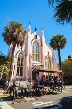 Photo for Charleston, South Carolina USA - October 9, 2013: Tourists enjoying a horse carriage ride by the historic French Huguenot Church located on Church Street - Royalty Free Image