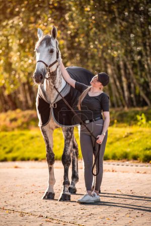 Photo for Female equestrian horse rider patting her gray horse. - Royalty Free Image