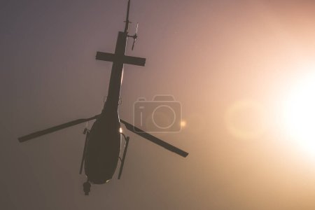 Photo for Helicopter Flying in the Sky Under the Shining Sun. Rotorcraft Machine in the Air Closeup. Ground View. Plain Background. - Royalty Free Image