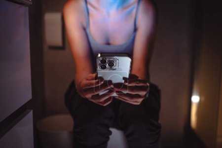 A woman uses a phone in the toilet