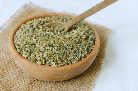 Photo for Raw freekeh or firik in a wooden bowl on burlap with a wooden spoon. Concept of healthy eating. Rustic style. Horizontal orientation. Selective focus. - Royalty Free Image