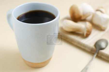 Mushroom coffee in a blue cup with mushrooms on a yellow background. The concept of a trendy beverage. The drink is good for health. Horizontal orientation. Selective focus.