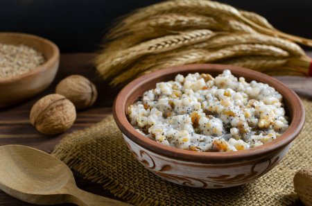 Photo for Kutya, a traditional Christmas Ukrainian dish of wheat groats on the table for Christmas or the old new year. Boiled porridge with walnuts, raisins, poppy seeds and honey. Rustic style. - Royalty Free Image