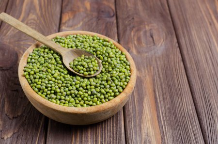 Green mung beans in a bowl with a spoon on a wooden table. Organic legumes. Vegan and vegetarian food. Rustic style. The concept of healthy eating. Horizontal orientation. Copy space. Selective focus.