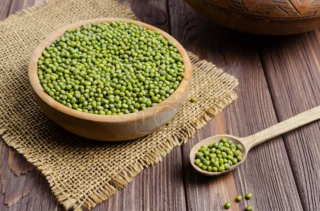 Green mung beans in a bowl with a spoon on a wooden table. Organic legumes. Vegan and vegetarian food. Rustic style. The concept of healthy eating. Horizontal orientation. Selective focus.