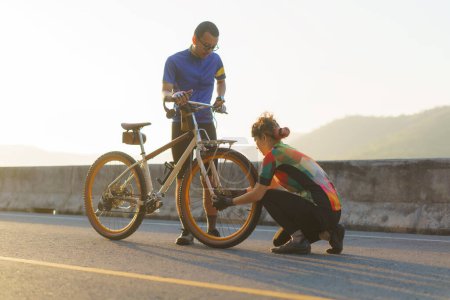Téléchargez les photos : Asian cyclist couple assembles bikes for a morning bike ride by the lake. - en image libre de droit