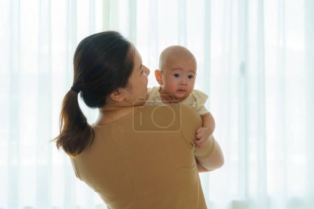 Téléchargez les photos : Mère asiatique tient son fils nouveau-né dans la chambre à coucher à la maison, représentant l'amour et le lien entre la mère et le fils. - en image libre de droit