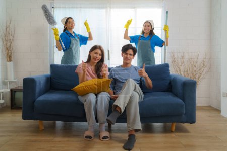Photo for Satisfied Asian homeowner gives a thumbs-up, expressing delight and approval for the exceptional cleaning service provided by the diligent Asian maid - Royalty Free Image