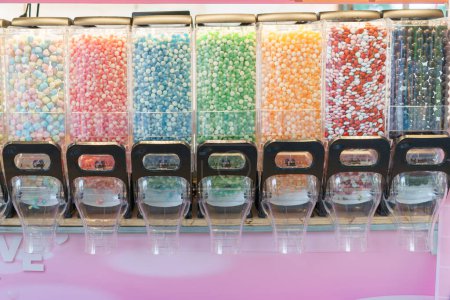 Téléchargez les photos : Un affichage vibrant de distributeurs de bonbons remplis d'une variété de bonbons colorés, offrant un choix délicieux pour ceux qui ont une dent sucrée - en image libre de droit