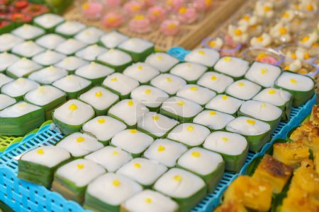 Téléchargez les photos : Pudding thaïlandais avec garniture de noix de coco, connu sous le nom de 'Khanom Tako', présenté dans de petites tasses de feuilles de banane, surmonté de délicats haricots jaunes, un dessert thaïlandais classique - en image libre de droit