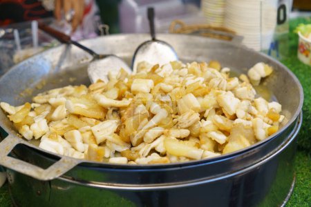 Fresh squid being fried to perfection in a large pan at a bustling street food market, a popular snack among locals and tourists alike