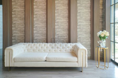 Erleben Sie die Verschmelzung von Komfort und Stil in diesem schicken Wohnbereich. Das Herzstück, ein luxuriöses weißes Sofa, bietet einen einladenden Raum zum Entspannen. Strukturierte Ziegel- und Holzakzente schaffen eine zeitgemäße und doch warme Kulisse