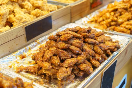 Téléchargez les photos : De généreuses portions d'ailes de poulet glacées au miel, scintillantes et parfaitement cuites, exposées dans un étal de marché alimentaire - en image libre de droit