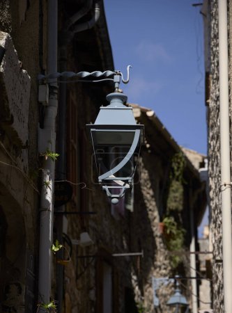 Foto de Lámpara. Lámpara de calle de metal colgando en la pared de una casa rústica - Imagen libre de derechos