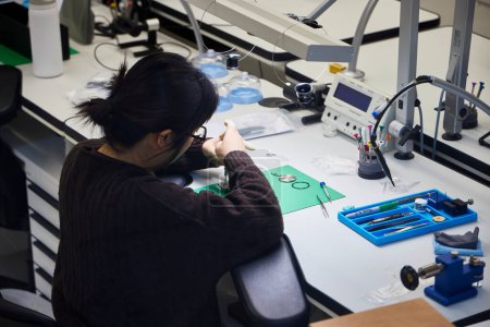 Foto de Nueva York (Estados Unidos), 22 de marzo de 2024. Reparando relojes. Una mujer arregla un reloj en el taller de servicio técnico - Imagen libre de derechos
