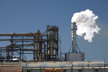 Foto de Padrn (España), 16 de abril de 2024. Contaminación. Una chimenea de fábrica liberando una nube de humo contaminante en el aire. - Imagen libre de derechos