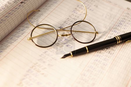 Glasses on desk. Antique glasses and a fountain pen on an accounting book