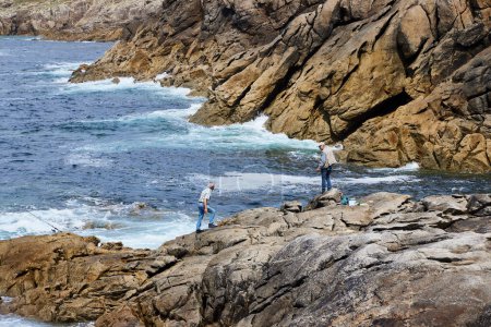 Photo for Punta Roncudo (Spain), May 9, 2024. Fishermen. Fishermen casting their rod into the water on a cliff on the Costa de la Muerte, a dangerous part of the Galician coastline. - Royalty Free Image