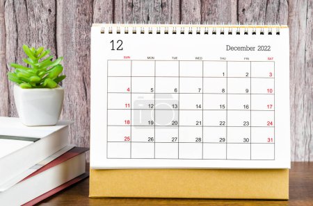 Diciembre 2022 Calendario mensual de escritorio para 2022 años con los libros sobre mesa de madera.