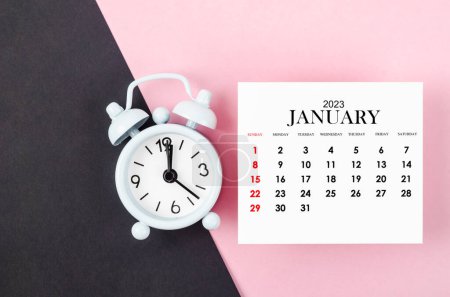 Foto de Enero 2023 Año calendario mensual con despertador sobre fondo rosa. - Imagen libre de derechos