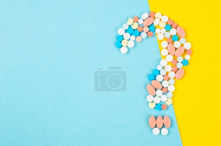 Photo for Question mark from laid out of medicine pills with bottle drug on blue background. - Royalty Free Image