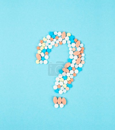 Photo for Question mark from laid out of medicine pills on blue background. - Royalty Free Image