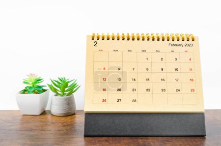 Februar 2023 Monatlicher Schreibtischkalender für das Jahr 2023 mit kleiner Pflanze auf Holztisch.