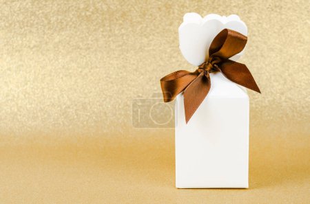 Foto de Caja de regalo con cinta marrón sobre fondo de navidad de textura de brillo dorado. - Imagen libre de derechos