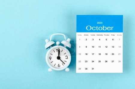 Octubre 2023 Calendario mensual para 2023 año con reloj despertador vintage sobre fondo azul.