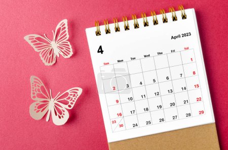 Foto de Abril 2023 escritorio del calendario para que el organizador planifique y recuerde con un peer de mariposa sobre fondo rojo. - Imagen libre de derechos