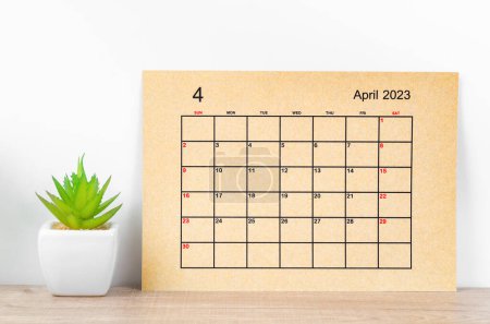 Brauner April 2023 Monatskalender für das Jahr 2023 mit Pflanzkübel auf Holztisch.