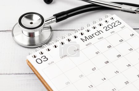 Stethoskop Medical und März 2023 Schreibtischkalender auf hölzernem Hintergrund, Zeitplan zur Überprüfung gesunder Konzepte.